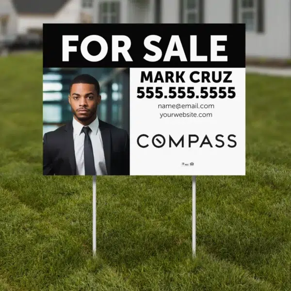 A real estate yard sign for Compass brokerage, displayed in front of a modern home.